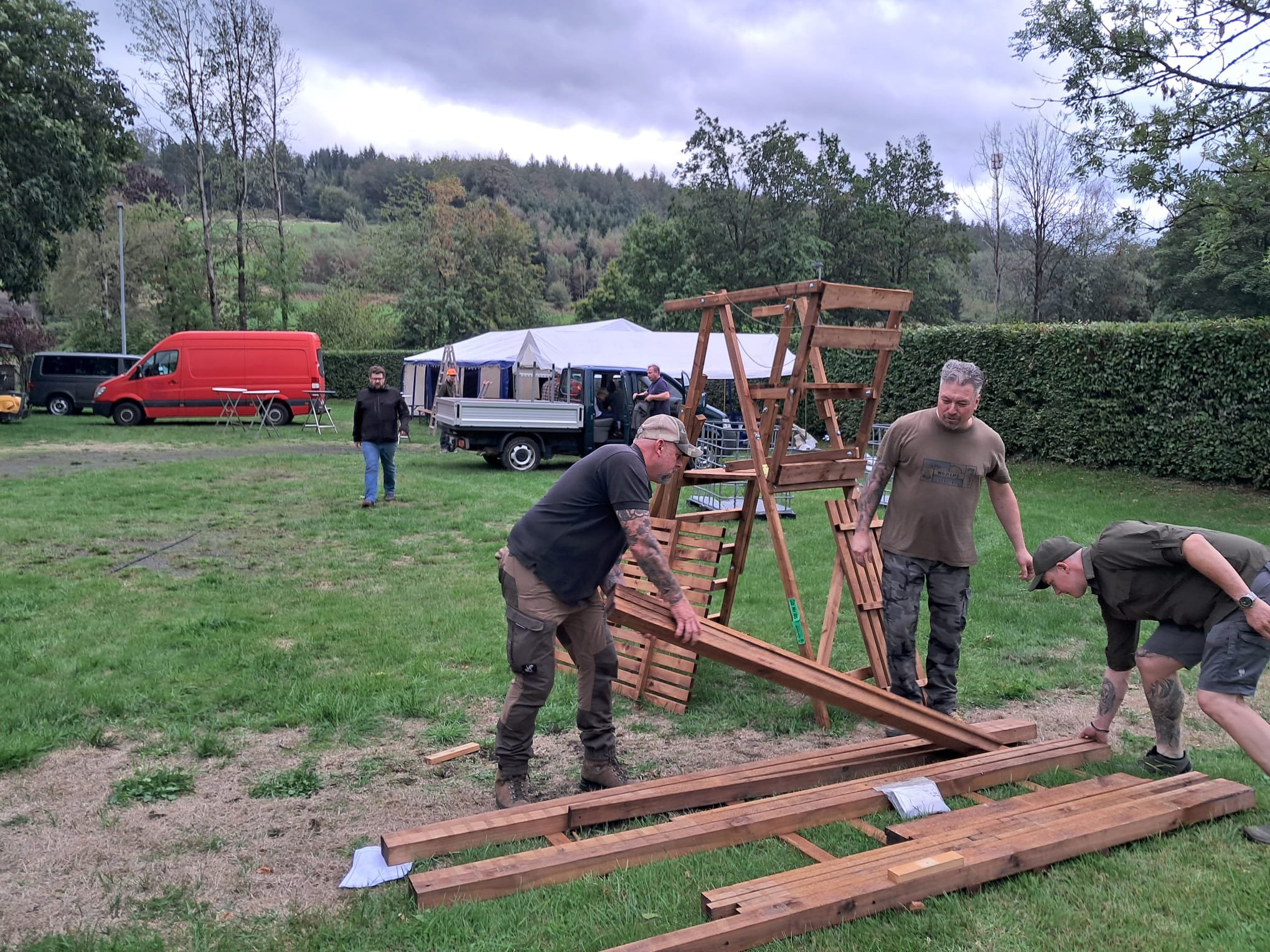 Helfer setzen einen Hochsitz auf der Wiese zusammen