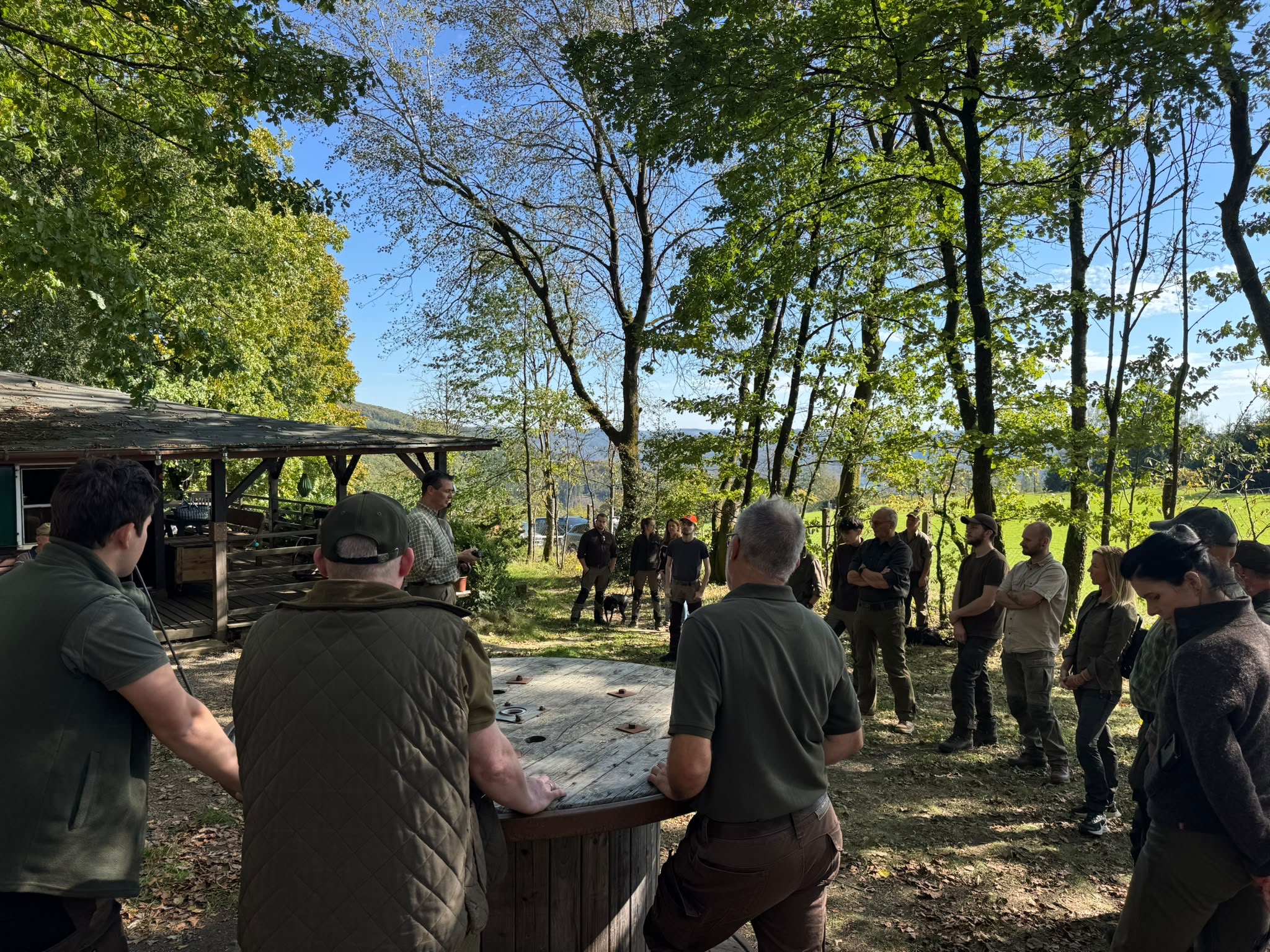 Teilnehmer hören an der Jagdhütte dem Vortrag zu